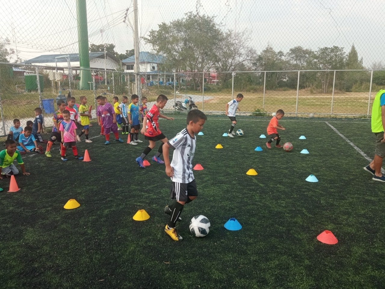 Volunteer coach running football drills with kids in Hua Hin, Thailand