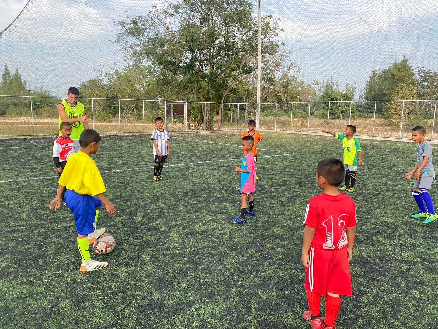 Young players dribbling during a volunteer-led football session in Hua Hin