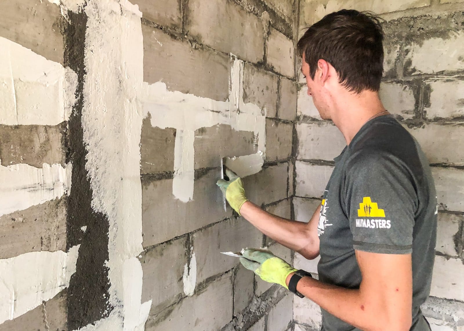 Volunteer rendering a brick wall on a Nepal construction placement