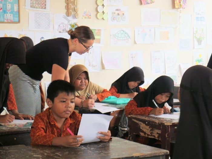 Volunteer teacher helping students with classwork in Lombok