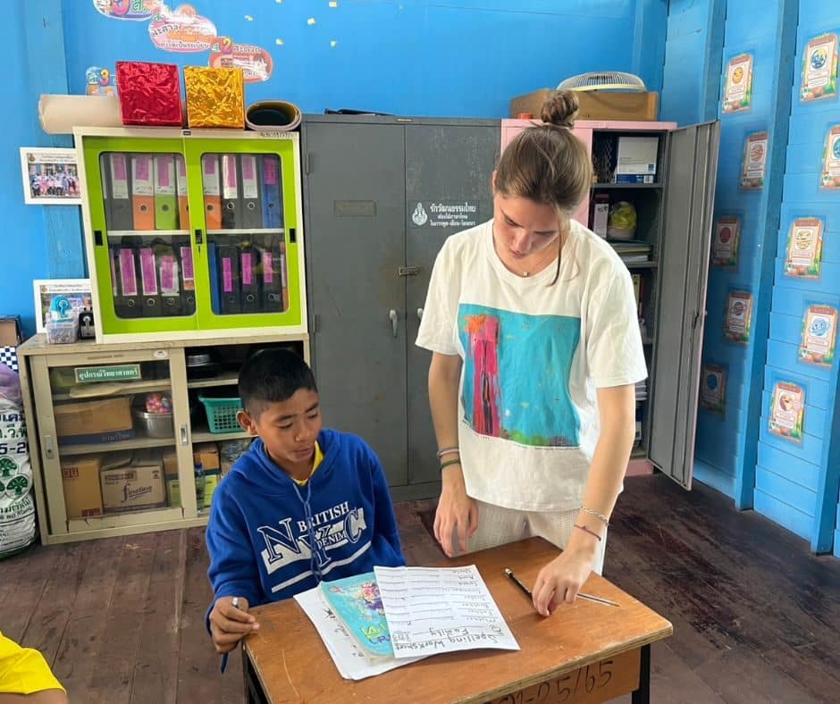 Volunteer helping a student with an English worksheet in Thailand